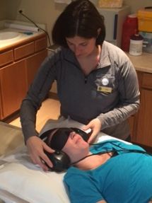 Tech putting headphones and sleep mask on patient