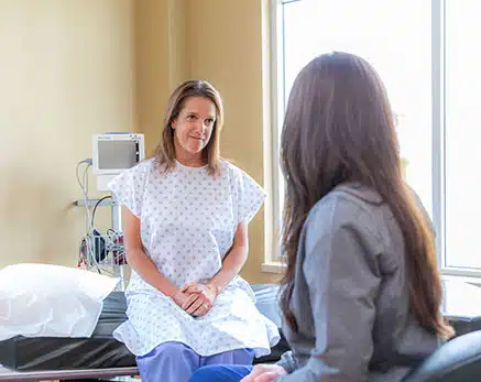Patient in scrubs sitting in exam room with doctor
