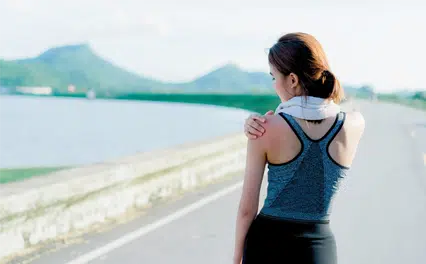 female runner holding shoulder
